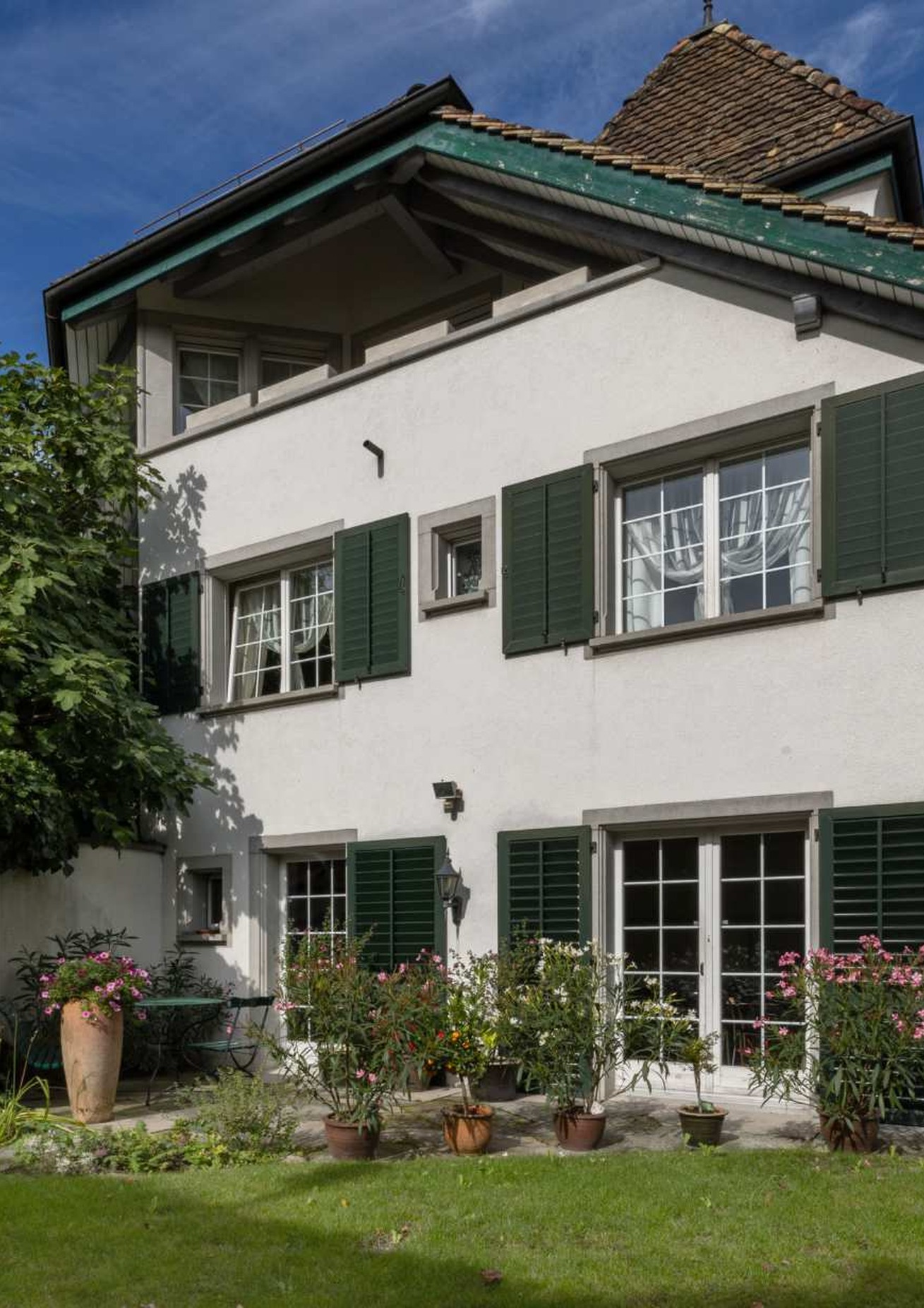 Gartenfassade der Landhausvilla mit grünen Fensterläden